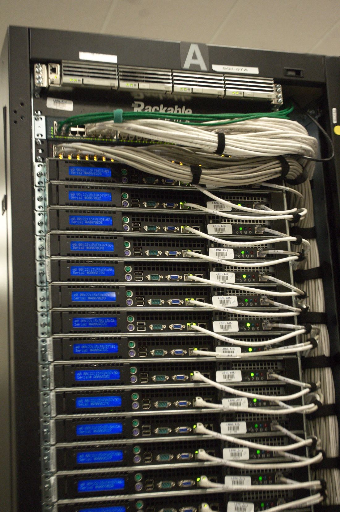 Back of a server rack with cables and small blue status displays